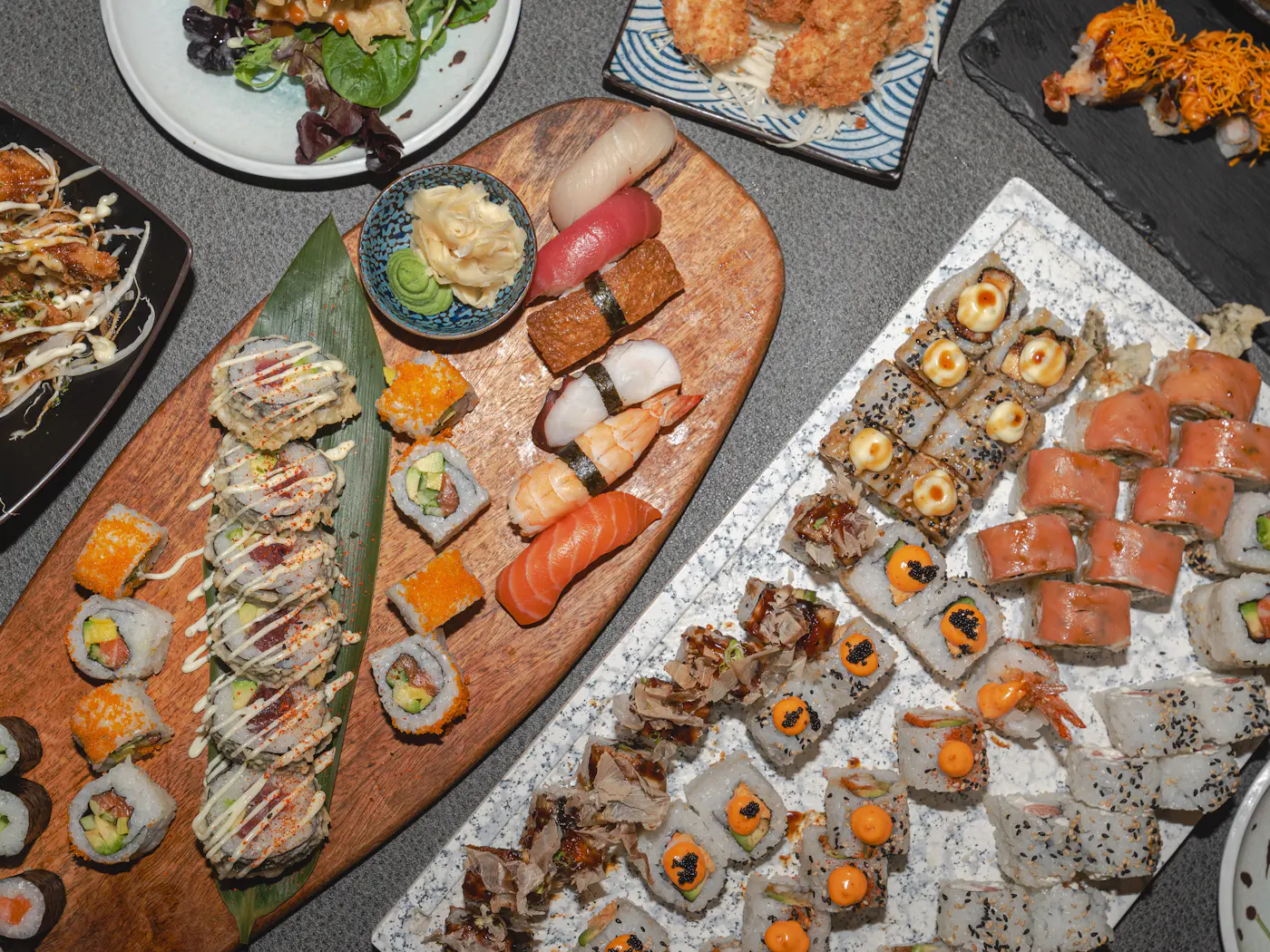 Mesa con varias bandejas de rolls y nigiris